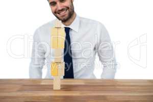 Businessman placing wooden block on a tower