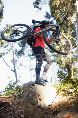 Male mountain biker carrying bicycle in the forest