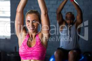 Smiling female athlete exercising in gym