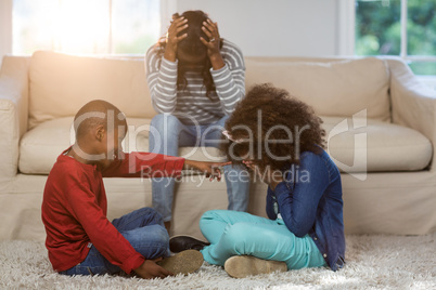 Children playing while mother sitting depressed