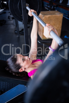 Young female athlete lifting barbell