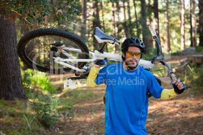 Male mountain biker carrying bicycle in the forest