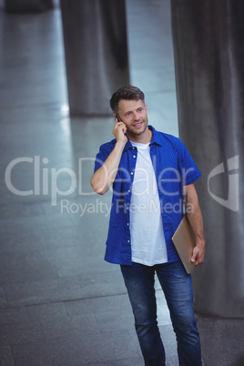 Handsome man holding laptop and talking on mobile phone