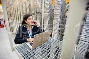 Technician talking on mobile phone in server room