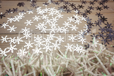 Small candles and snowflake scattered on wooden table