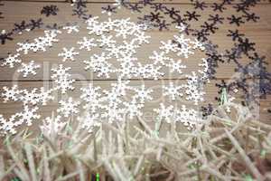 Small candles and snowflake scattered on wooden table