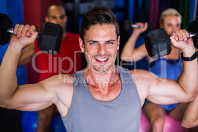 Portrait of smiling man lifting dumbbell in gym