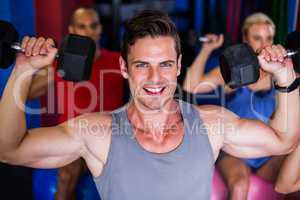 Portrait of smiling man lifting dumbbell in gym