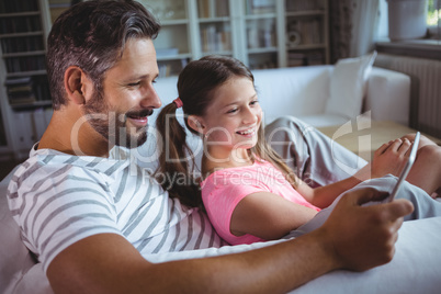 Father and daughter using digital tablet in living  room