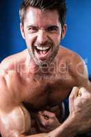 Portrait of cheerful shirtless athlete flexing muscles