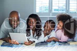 Family using digital tablet on bed