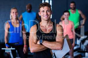 Portrait of smiling gym trainer holding clipboard