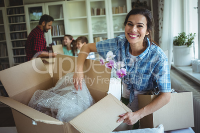Woman unpacking cartons while family standing in background