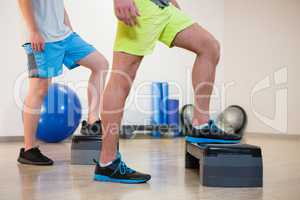 Two men doing step aerobic exercise on stepper