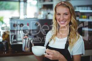 Portrait of smiling waitress making cup of coffee