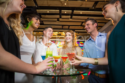 Group of friends interacting with each other while having cocktail