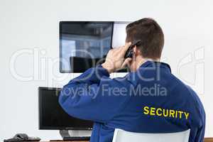 Security officer talking on walkie-talkie while looking at computer monitors