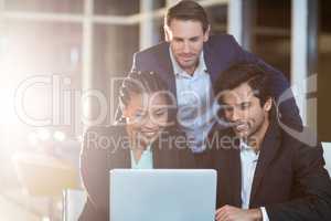 Businesswoman discussing with colleagues over laptop