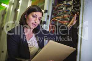 Technician using laptop while analyzing server