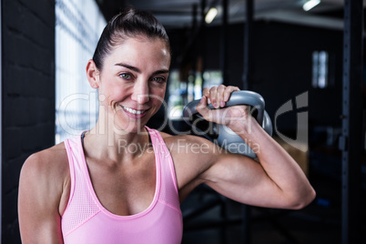 Smiling female athlete lifting kettlebell