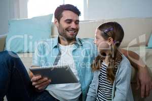 Father and daughter using digital tablet in the living room