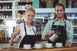 Portrait of waiter and waitress making cup of coffee at counter