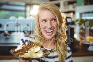 Smiling woman holding a plate of desserts
