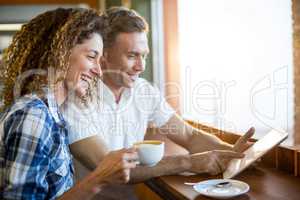 Happy couple using digital tablet in cafÃ?Â©