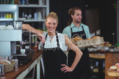 Portrait of smiling waitress standing behind counter