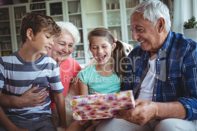 Grandparents and grandchildren looking at surprise gift in living room