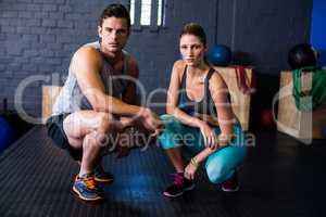 Confident athletes crouching in fitness studio