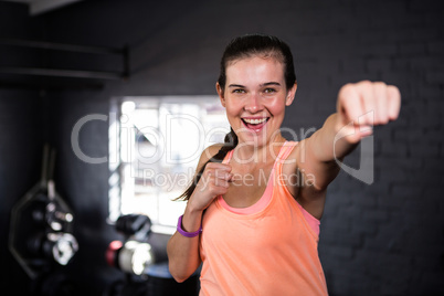 Smiling young woman punching in gym
