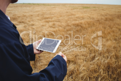 Thoughtful farmer standing with arms crossed in the field