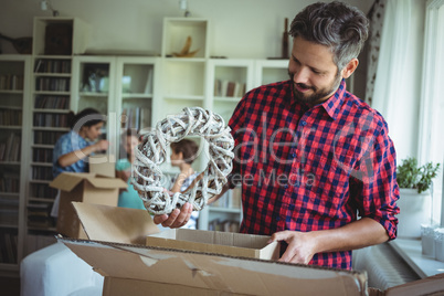 Man unpacking cartons while family standing in background