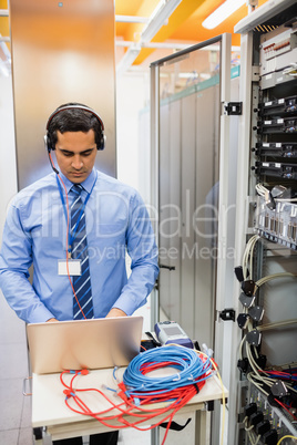 Technician in head phones using laptop