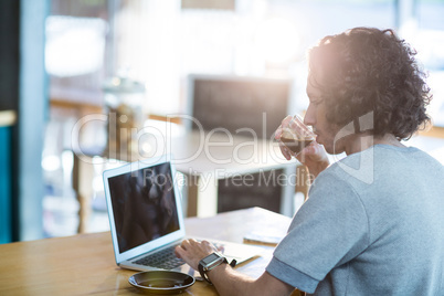 Man using a laptop while having cup of coffee