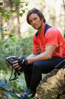 Portrait of exhausted male mountain biker relaxing on a tree trunk in the forest
