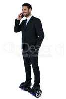 Businessman on hoverboard talking on mobile phone