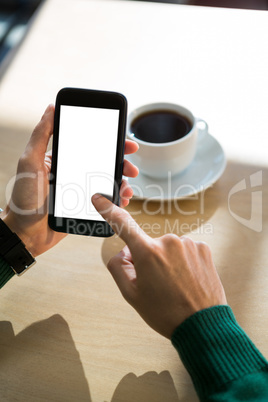 Hand using mobile phone with cup of coffee in table