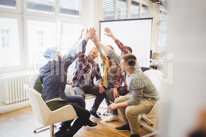 Creative business people giving high-five in meeting room