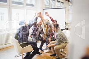 Creative business people giving high-five in meeting room