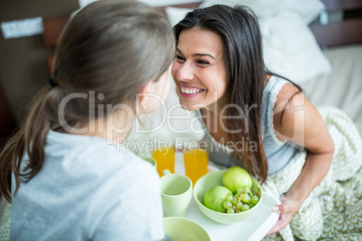 Mother and daughter having breakfast on bed