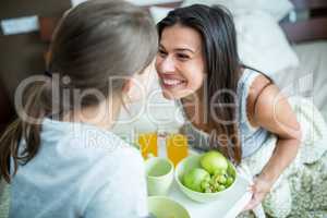 Mother and daughter having breakfast on bed