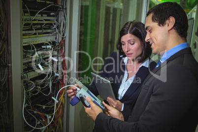 Technician working on personal computer while analyzing server Technicians using digital cable analy
