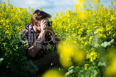 Man taking picture from camera in mustard field