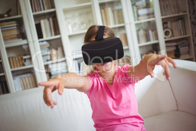 Happy girl looking through virtual reality headset in living room