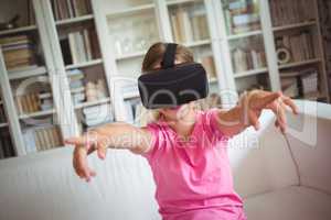 Happy girl looking through virtual reality headset in living room