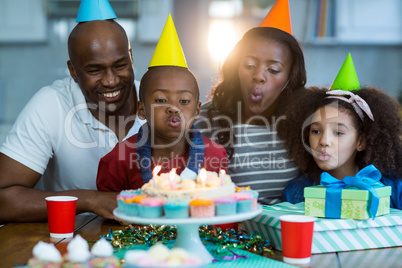 Family blowing out candles on birthday cake