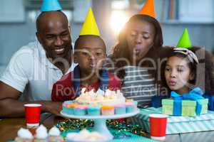 Family blowing out candles on birthday cake