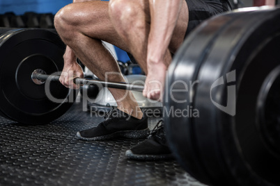 Low section of man lifting barbell